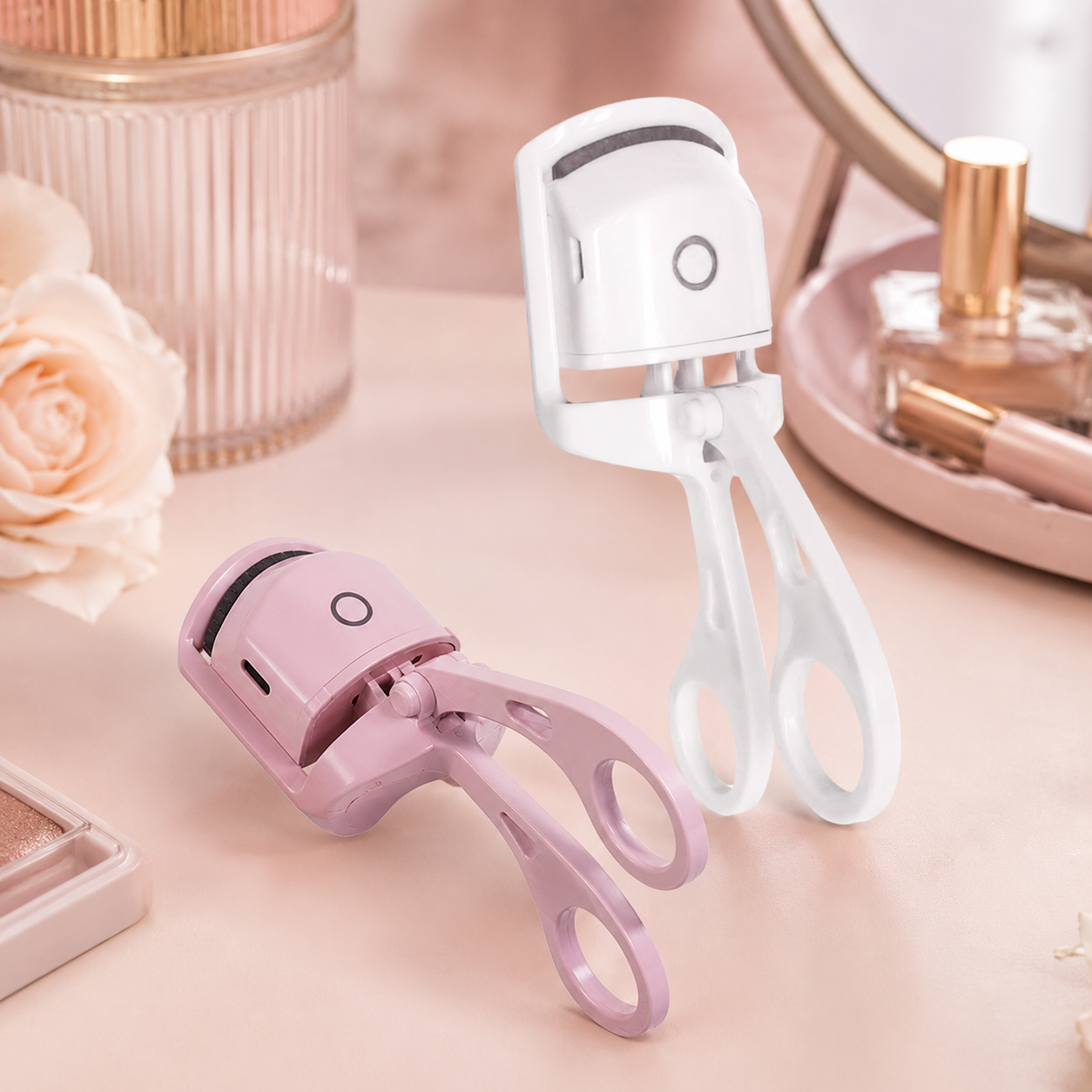 Pink and white heated eyelash curlers on a beauty vanity